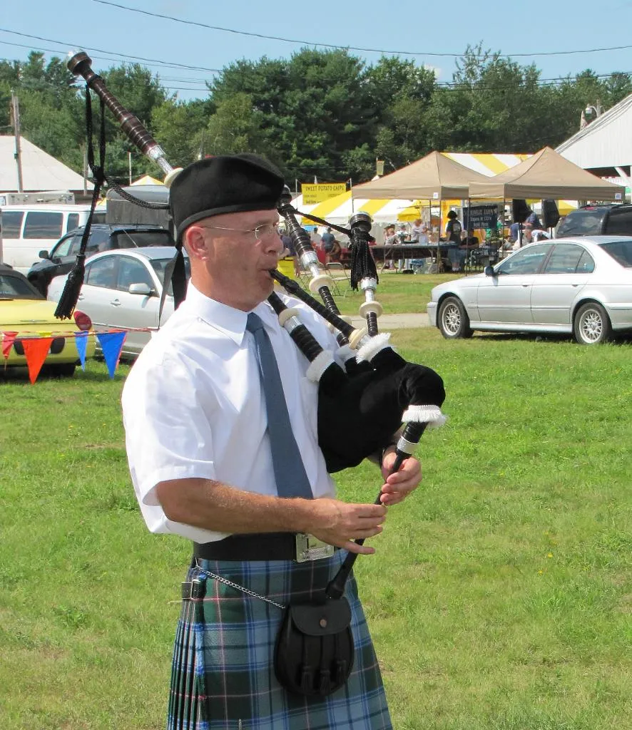 An MSAPD piper playing outdoors at a summer Highland games