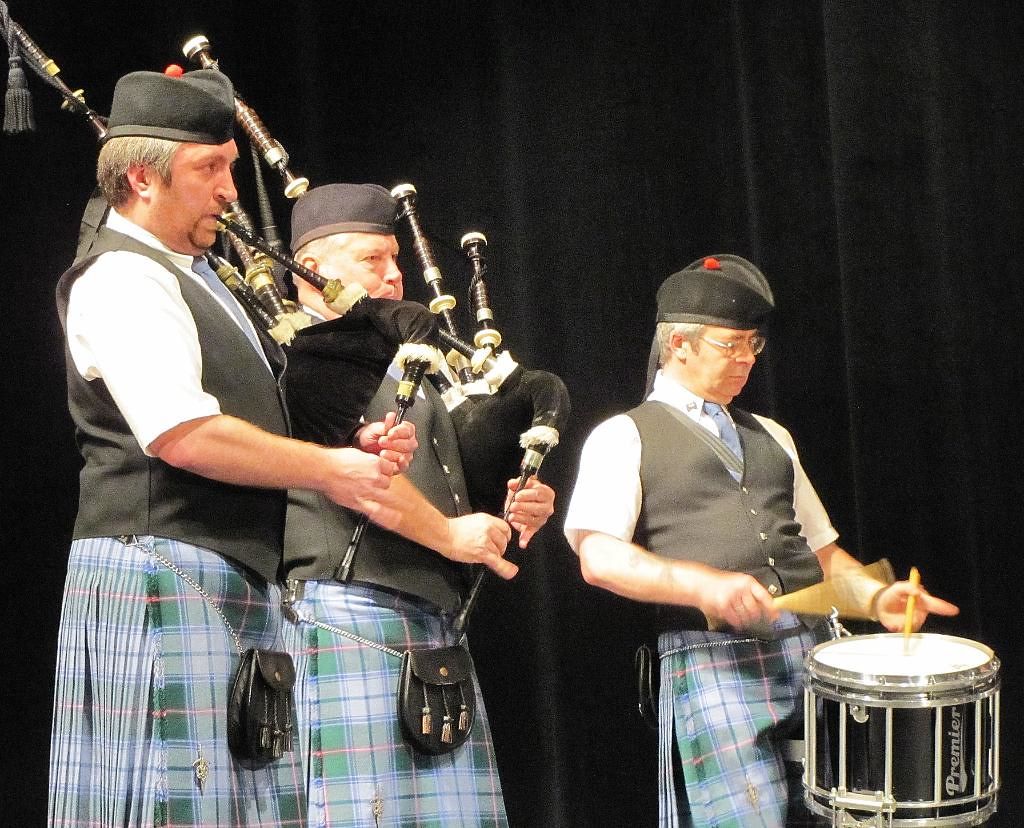 Two MSAPD pipers and a snare drummer in Maine State Tartan kilts performing on a concert stage